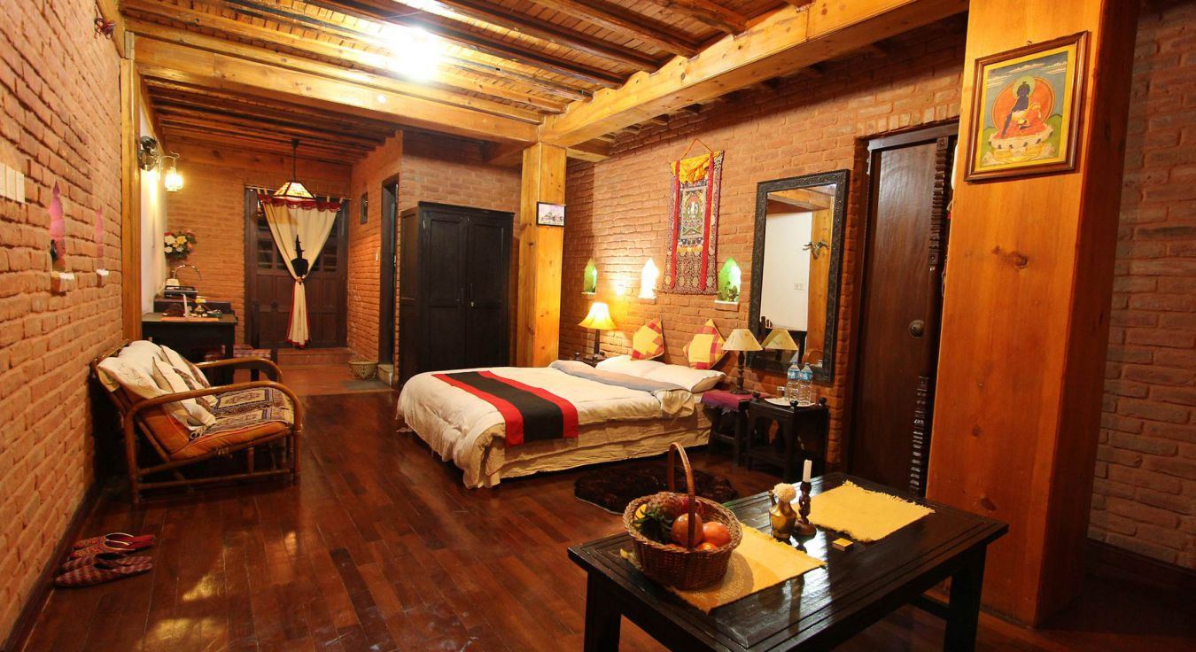 Heritage Deluxe room with brick walls, carved wood and a thangka